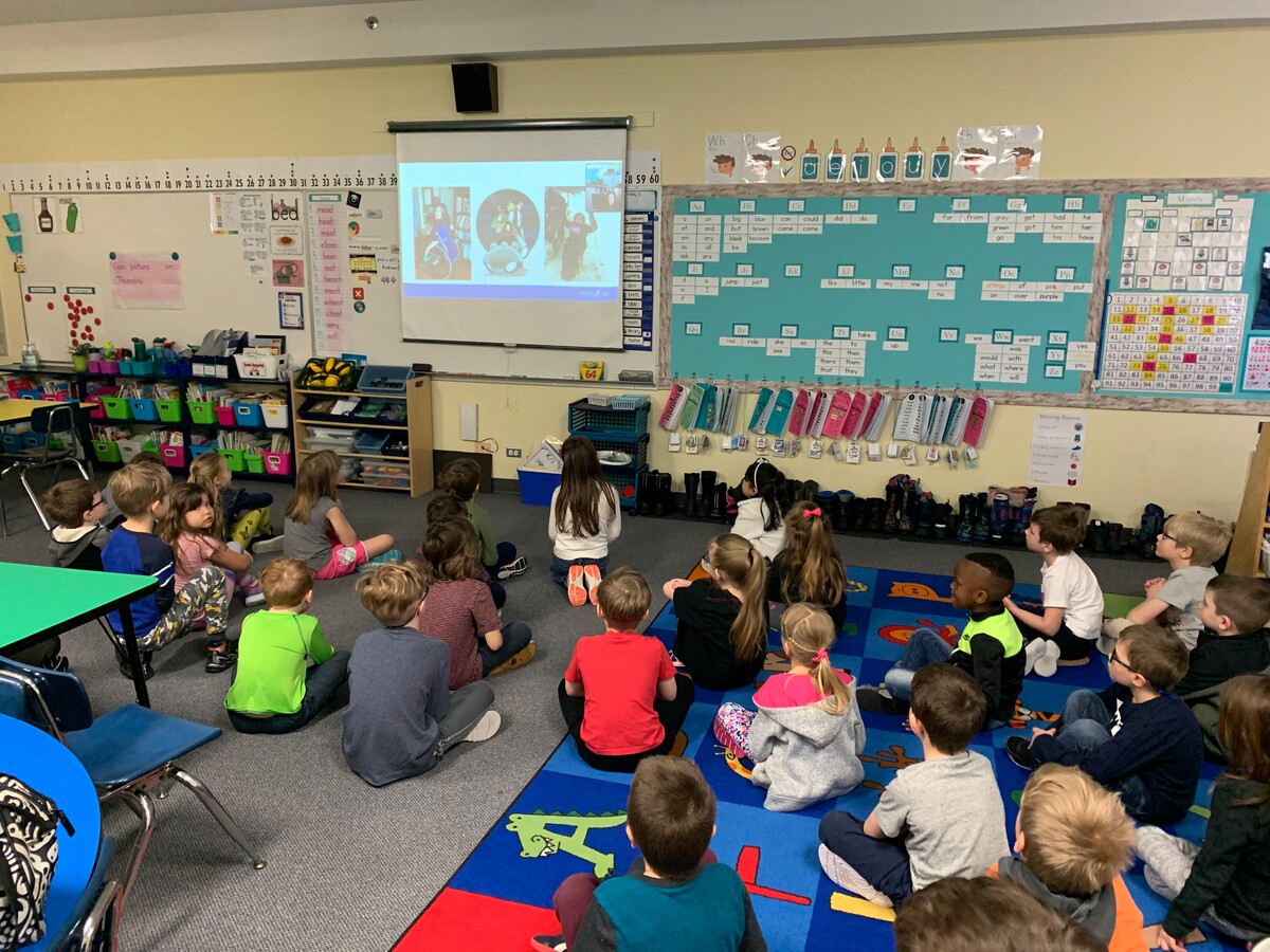 Classroom with students watching a virtual RHF Ambassador presentation on a projector screen.